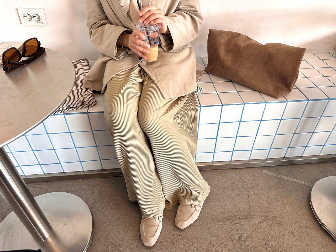 about-02 Casually dressed individual enjoying iced coffee in a modern café setting.
