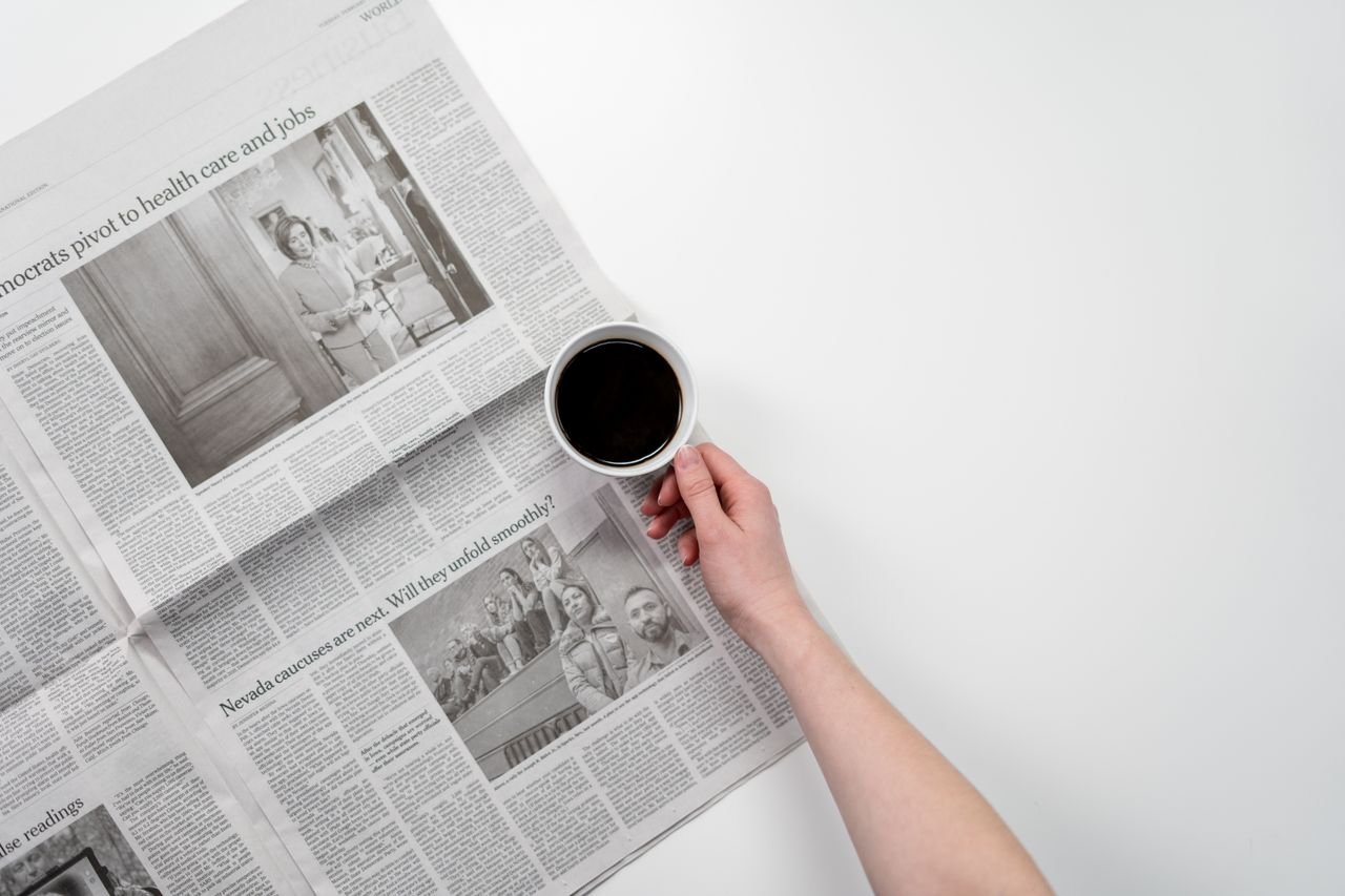 services-03 Hand holding a black coffee over newspaper, perfect for business and morning themes.